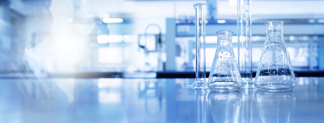 Wall Mural - shadow of scientist and glass flask and cylinder in medical science lab blue banner background