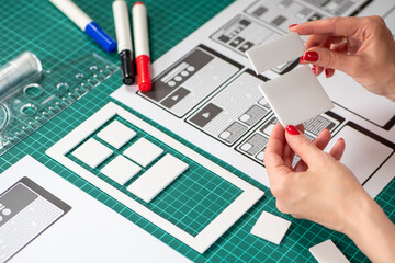 Wall Mural - work on application design. designer hands with paper mockup of mobile app. designer ponders archite