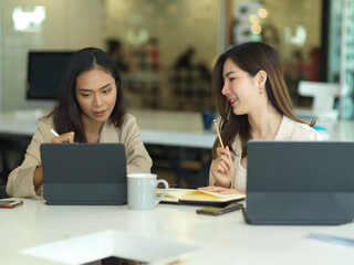 Businesswomen talking to each other while working in meeting room