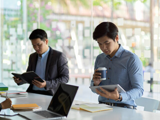 Two businessmen working on their work while sitting next to each other in office room