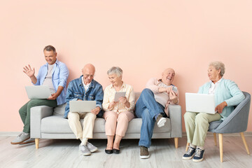 Wall Mural - Senior people with different devices sitting on sofa in room