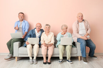 Canvas Print - Senior people with different devices sitting on sofa in room