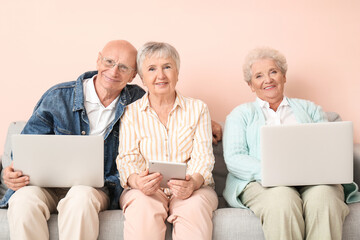 Canvas Print - Senior people with different devices sitting on sofa in room