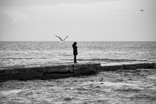 Lonely Female Figure On Breakwater Of Seashore
