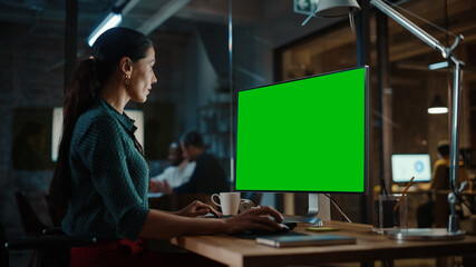Aufkleber - Middle Aged Multiethnic Specialist Working on Desktop Computer with Green Screen Mock Up Display in Busy Creative Office. Beautiful Diverse Female Manager in Green Polka Dot Blouse.