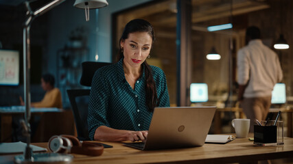 Aufkleber - Middle Aged Multiethnic Marketing Specialist Working on Laptop Computer in Busy Creative Office. Beautiful Diverse Multiethnic Female Project Manager is Writing Down Notes in Notebook.
