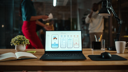 Shot of a Laptop Computer Standing on a Desk in a Busy Creative Office Environment. Display Shows Development of Food Delivery App User Interface. Authentic Hipster Agency Vibe. 