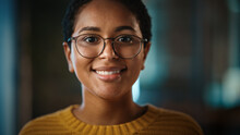 Close Up Portrait Of A Young Non-Binary Latina With Short Dark Hair And Glasses Posing For Camera In Creative Office. Beautiful Diverse Multiethnic Hispanic Female Is Happy And Smiling.