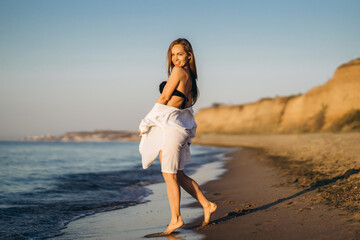 Wall Mural - Pretty brunette woman relaxing on the beach at the sea.