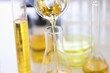 Yellow liquid flowing from test tube to flask in laboratory closeup. Quality control of petroleum products concept