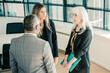 © Mangostar - Focused business group standing and talking in office, talking, discussing project and work issues. Copy space. Business communication or briefing concept