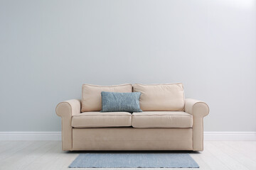 Wall Mural - Comfortable beige sofa near light wall indoors, space for text. Simple interior