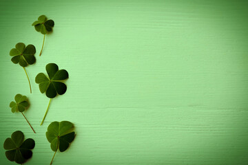 clover leaves on green wooden table, flat lay with space for text. st. patrick's day symbol