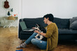 © cherryandbees - woman sitting on the floor in her living room and using laptop computer, holding her dog in lap