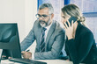 © Mangostar - Focused business colleagues working together, sitting at workplace, speaking on cellphone and using computer. Teamwork and communication concept
