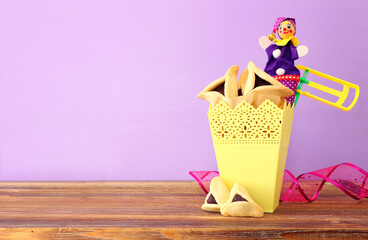 Purim celebration concept (jewish carnival holiday) over wooden table and purple background