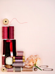 Assorted craft and sewing tools. Various bobbins, lace, ribbons and pins forming frame with copy space. Left bottom frame, mock up for tailoring business design.