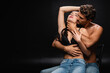 © LIGHTFIELD STUDIOS - passionate young couple in jeans embracing with closed eyes while sitting on chair on black