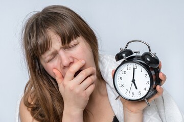 Wall Mural - Tired woman with alarm clock does not want waking up