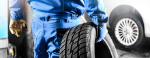 Mechanic Holding Tire With Copy Space For Text Repair Service Center, Blurred Background,