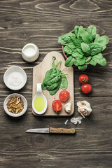 Ingredients for preparing salad on a wooden background. Vegetable salad in a bowl, tomato, spinach, garlic, olive oil. Healthy, clean food concept. Vegan or gluten-free diet. Copy space