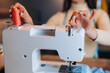 Close up young dressmaker woman with sewing machine. Creating online clothing design courses.