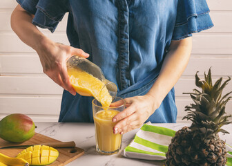 Wall Mural - Young woman pouring smoothie into glass