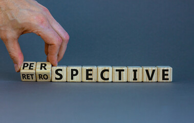 Perspective or retrospective symbol. Businessman hand turns cubes and changes word 'retrospective' to 'perspective'. Beautiful orange background. Business and perspective concept. Copy space.