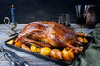 Traditional roasted stuffed Christmas goose with quinces and orange slices served as close-up on an old rustic tray