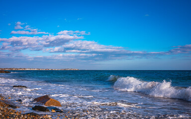 Wall Mural - Seascape with white waves and clouds over the rocky windy beach