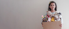 Mixed Asian Young Volunteer Girl Holding A Box Full Of Used Toys, Cloths, Books And Stationery For Donation