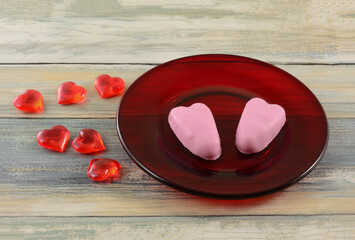 Sticker - Two pink heart chocolate Valentine's Day peanut butter candy on red glass plate with hearts on table