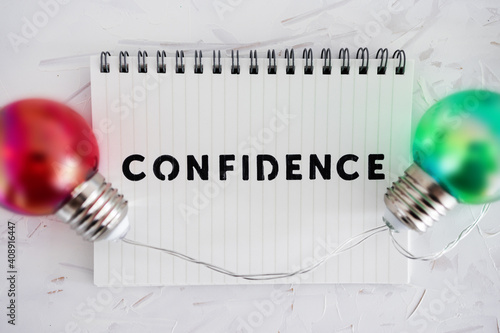 confidence text on notepad surrounded by colorful light bulbs symbol of ideas, positive attitiude and psychology