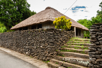 Okinawa traditional house made of wood, grass thatched roof and coral wall.