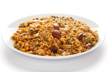 Wall Mural - 'Shahi Mixture' in a white ceramic plate, made with peanut, cashew, corn flakes, almonds, etc. Pile of Indian spicy snacks (Namkeen). Side view, against the white background