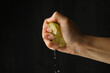 Female hand squeeze lime on black background