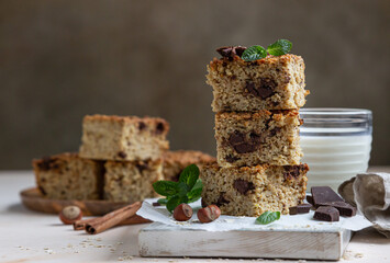 Wall Mural - Oatmeal squares with chocolate and a cup of milk, light concrete background. Diet bars. Healthy bakery for breakfast or dessert.