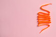 Orange shoelace on pink background, top view. Space for text