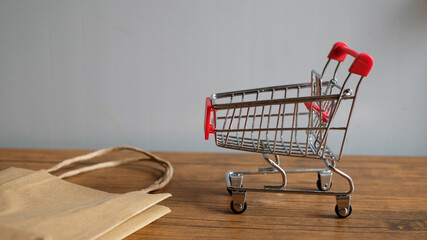 Shopping cart with shopping bag on table, e-commerce and online business technology.