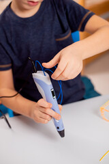 Focused child with 3d printing pen creating a toy