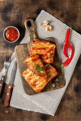 Wall Mural - Cooked smoked pork ribs on a wooden serving board on a brown wooden table. Fried smoked pork ribs