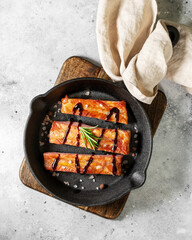 Wall Mural - Boiled smoked pork ribs in a black cast-iron skillet on a light gray kitchen table. Fried pork ribs