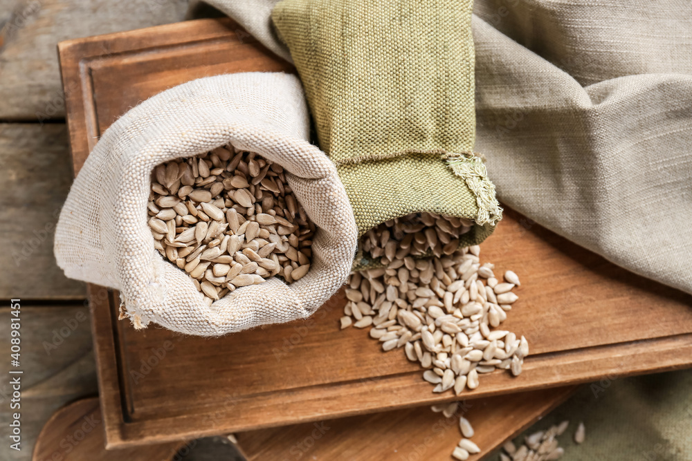 Bags with sunflower seeds on wooden background