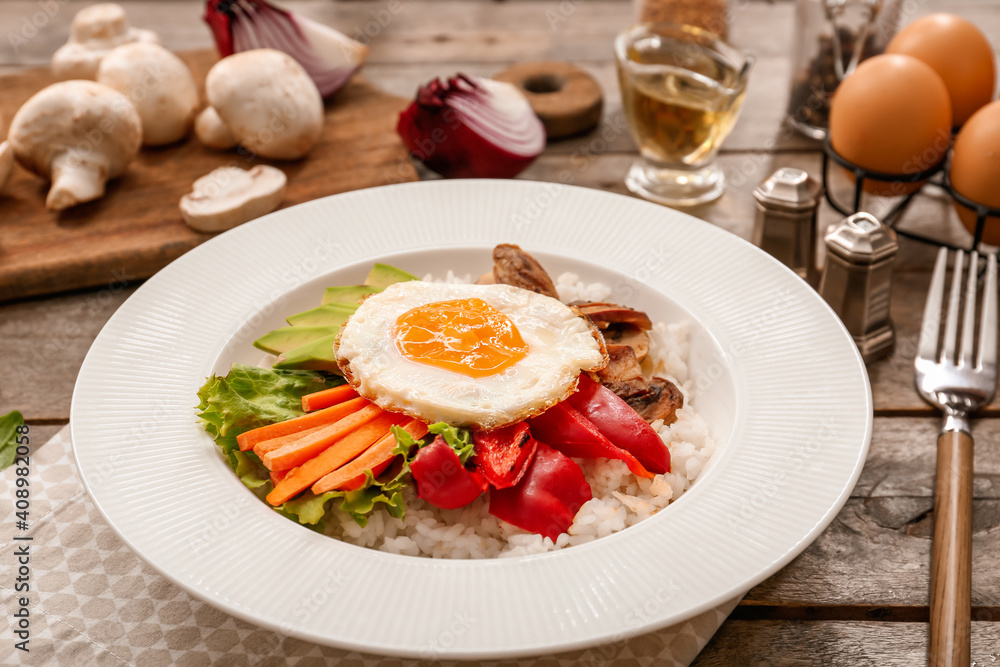 Plate with tasty egg, vegetables and rice on wooden background