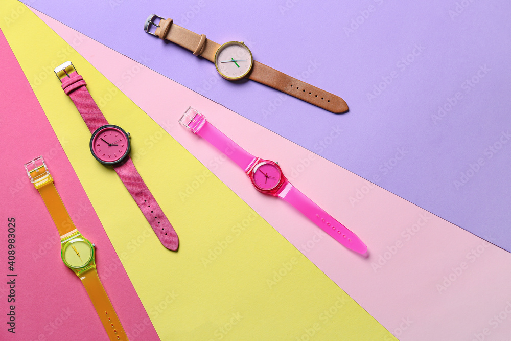 Stylish wrist watches on colorful background