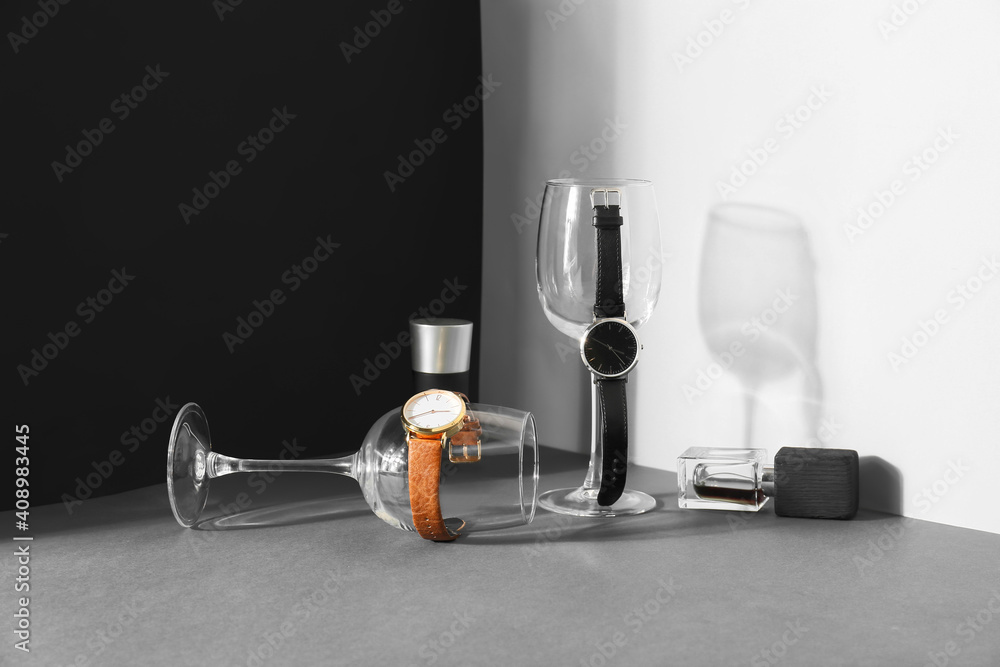 Composition with stylish wrist watches and glasses on dark background