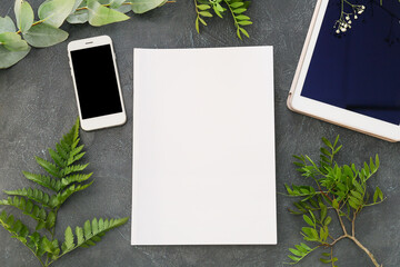 Blank magazine, tablet computer and mobile phone on dark background