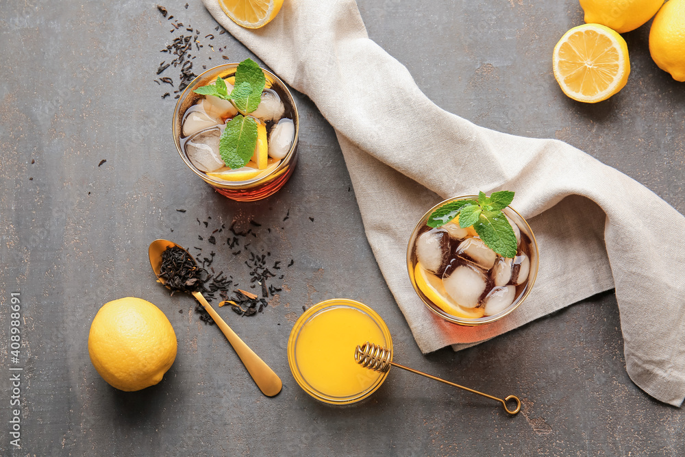 Glasses of cold black tea with lemon on dark background