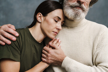 Serious mature father hugging and holding his military daughter's hand