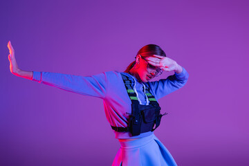 Wall Mural - young model in sunglasses covering face and posing with outstretched hand on purple